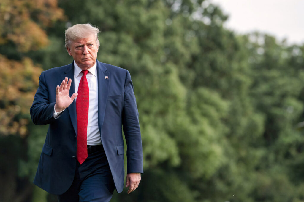 Washington DC, USA - August 21 2019: a serious looking president Donald Trump walking across the lawn of the White House, waving his hand in greeting gesture